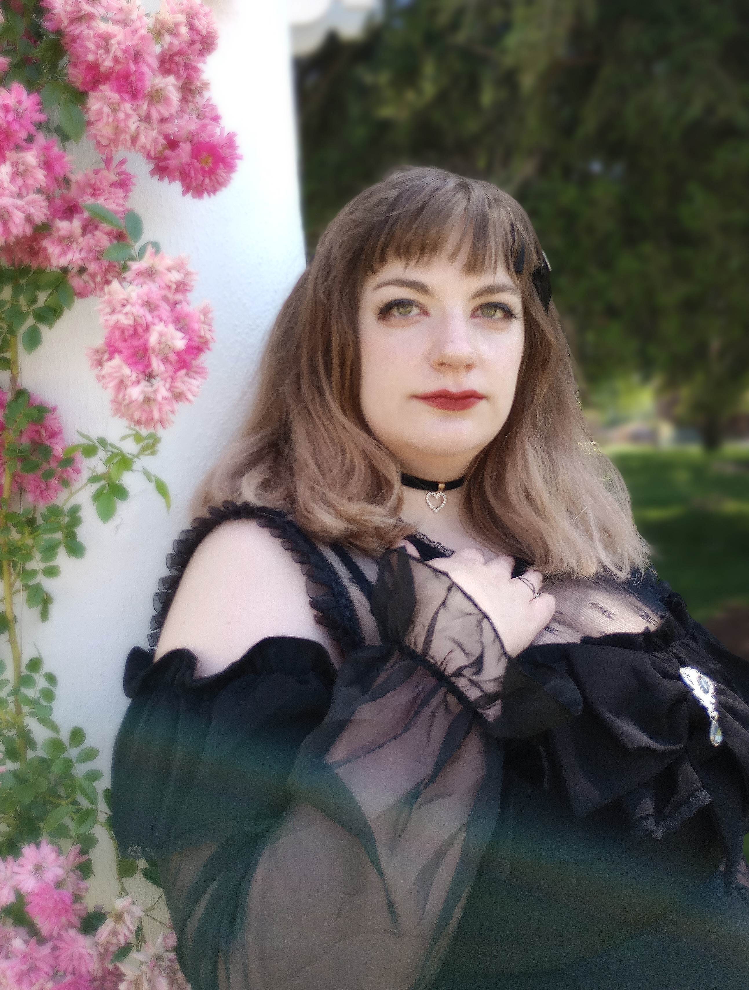 Person leans against white wall with flowers trailing down in the background.