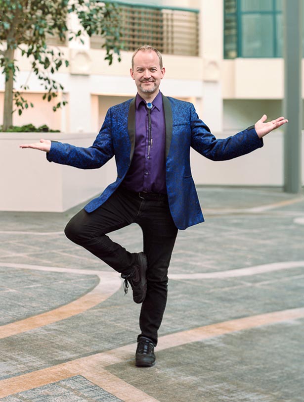 Smiling man in jacket and bolo tie does pose.