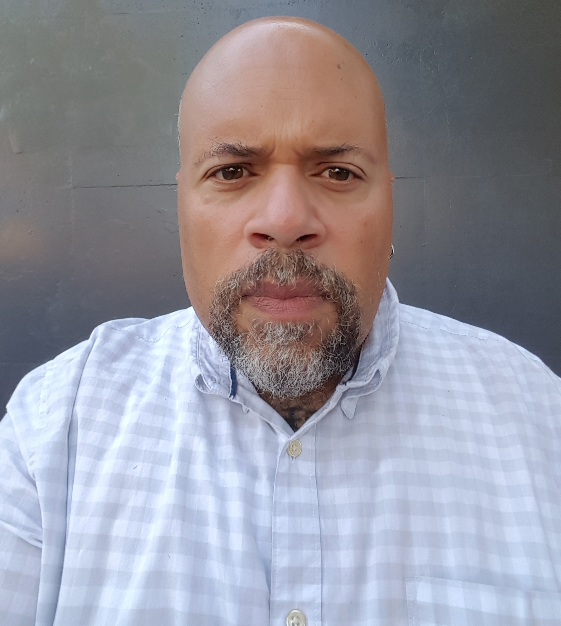 Person with goatee and earing looking on intensely.